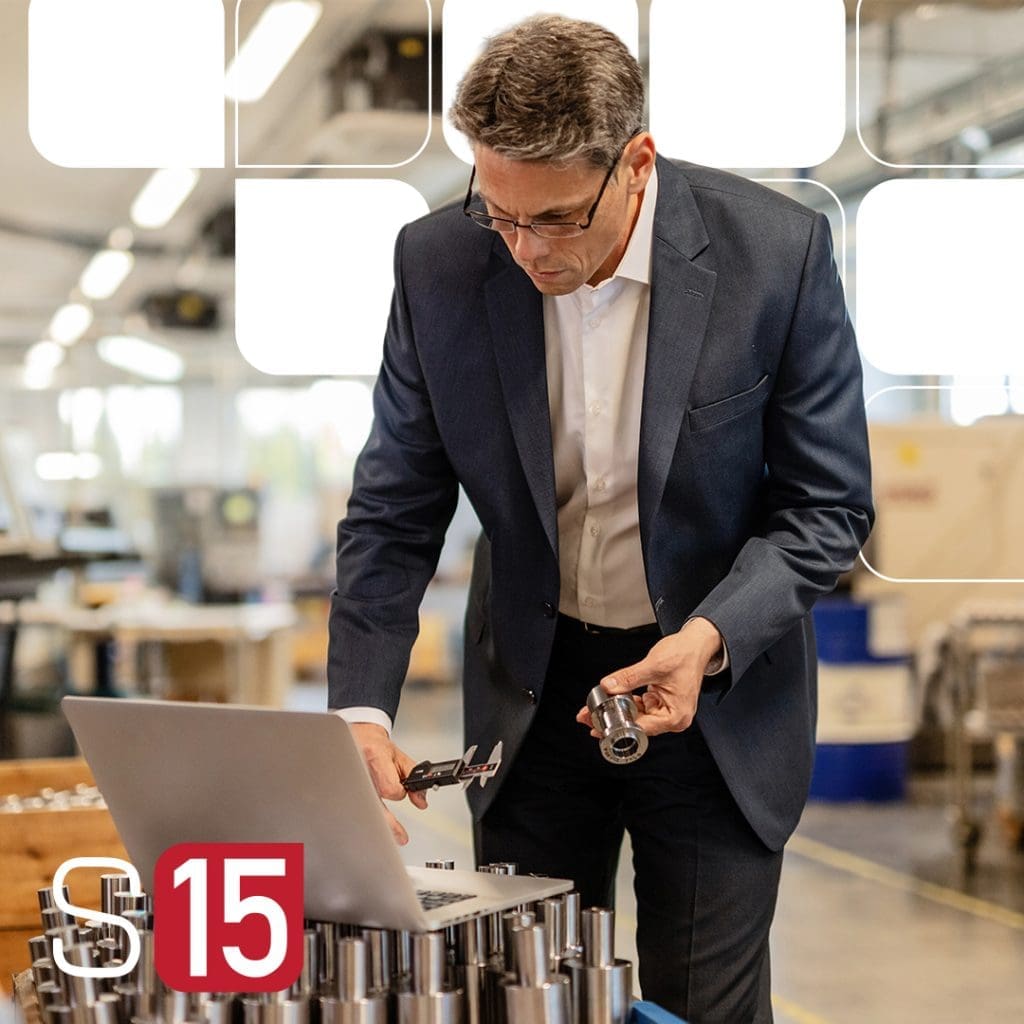 A man in a factory using a laptop
